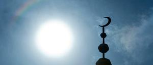 Der Halbmond auf dem Minarett der Abubakr Moschee in Frankfurt. hebt sich als Schattenriss vor der Sonne ab.