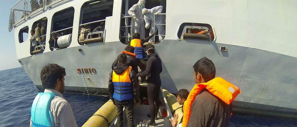 Die italienische Marine nimmt Bootsflüchtlinge auf.