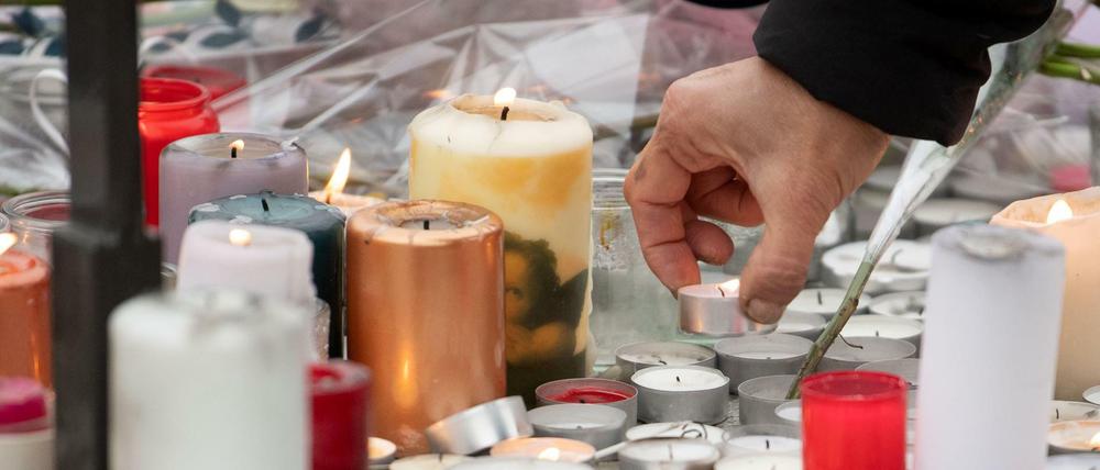 Eine Frau legt auf einem Sockel nahe des Weihnachtsmarktes in Straßburg eine Kerze hin.