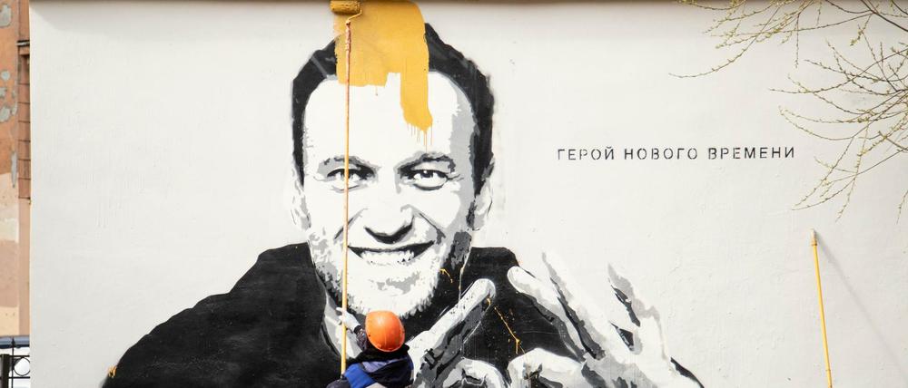 Arbeiter übermalen in St. Petersburg ein Graffiti mit dem Konterfei von Nawalny. Auf der Wand steht: „Held unserer Zeit“.