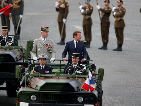 Emmanuel Macron (r, 2. Reihe) fährt vor Beginn der Militärparade zum Nationalfeiertag an den Soldaten vorbei. 