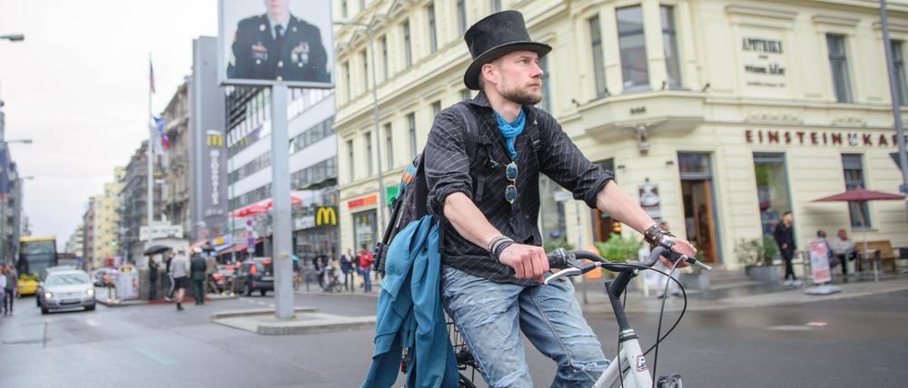 Juha Järvinen, Teilnehmer des Experiments Grundeinkommen in Finnland, fährt auf einem geliehenen Fahrrad am Checkpoint Charlie vorbei. 