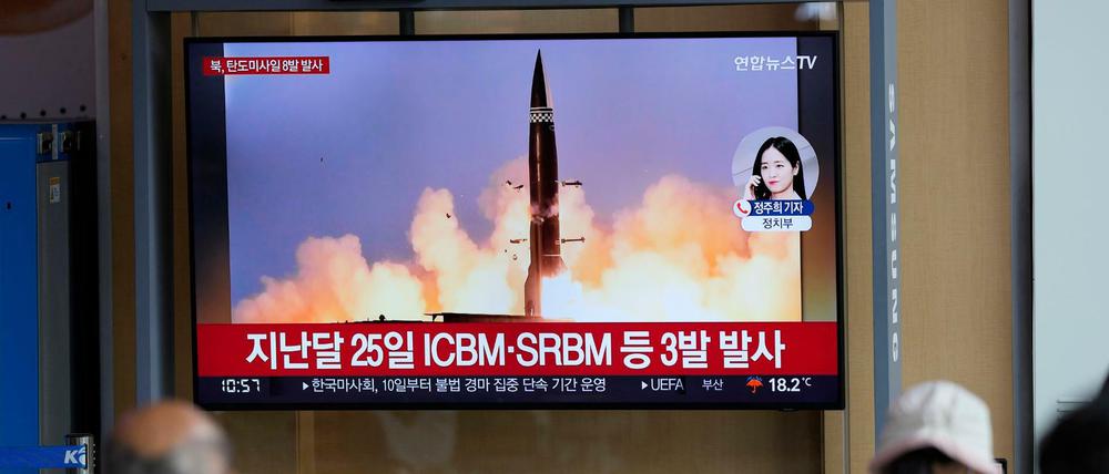 Menschen sehen einen Fernsehbildschirm, auf dem eine Nachrichtensendung über den nordkoreanischen Raketenstart gezeigt wird.