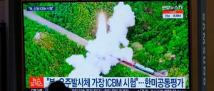 Eine Frau betrachtet einen Fernsehbildschirm in einem Bahnhof, auf dem eine Nachrichtensendung über Nordkoreas Raketen gezeigt wird. 