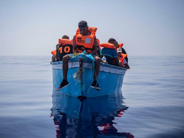 Eine Gruppe mutmaßlicher Migranten aus Tunesien sitzen an Bord eines Holzbootes und wartet auf Hilfe.