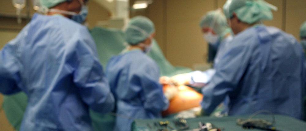 Chirurgen operieren in einer Klinik einen Patienten, im Vordergrund liegt Operationsbesteck.