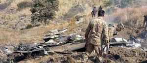 Pakistanische Soldaten untersuchen die Wrackteile eines indischen Kampfjets.