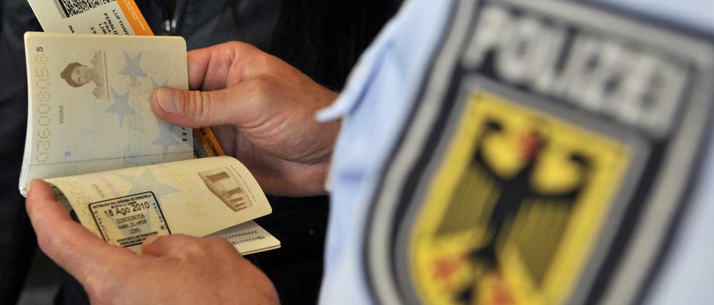 Ein Beamter der Bundespolizei kontrolliert am Frankfurter Flughafen einen Pass.