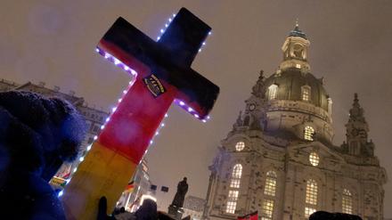 Anhänger der fremden - und islamfeindlichen Pegida-Bewegung demonstrieren im Februar 2016 mit einem beleuchteten Kreuz vor der Frauenkirche in Dresden (Sachsen).