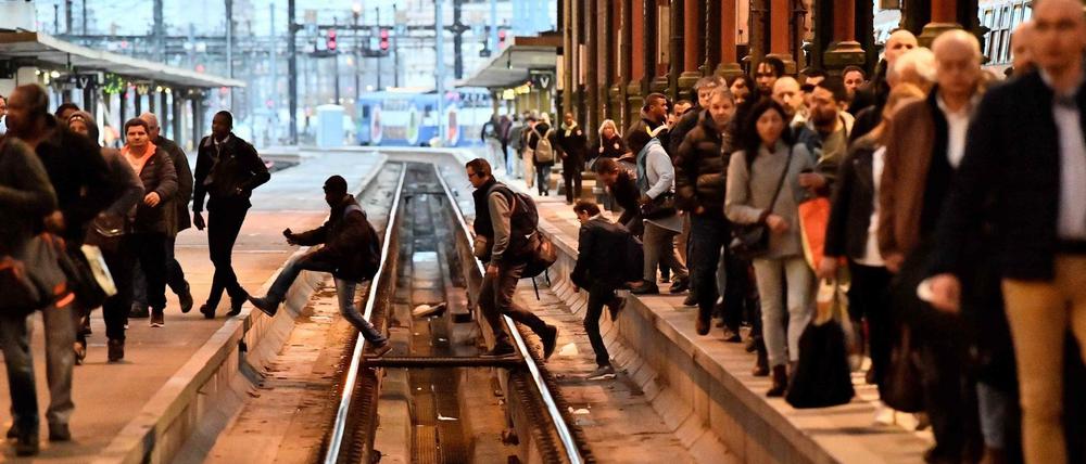 In einer Pariser Bahnstation laufen Leute über Gleise. In Frankreich hat am Dienstag ein massiver Eisenbahner-Streik begonnen.