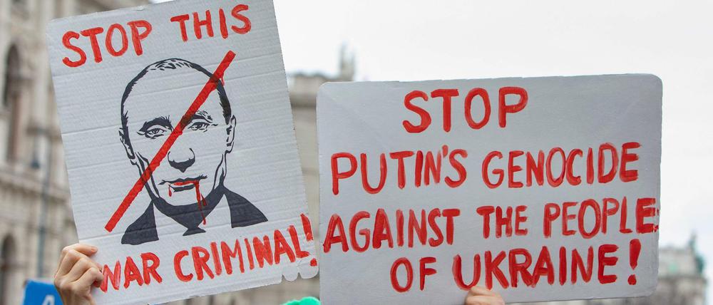 Bei einer Demonstration in Wien werden Schilder mit dem Gesicht Putins in die Höhe gehalten. 