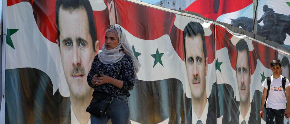 Passanten laufen an Assad-Plakaten in Damaskus vorbei.