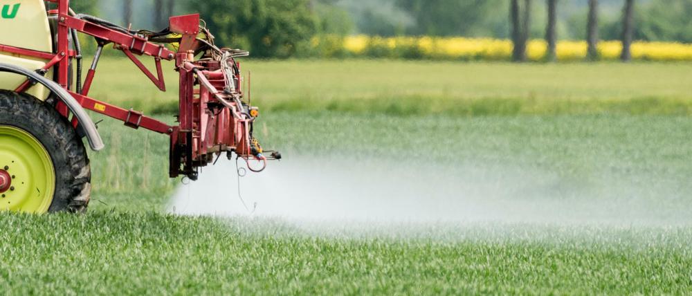 Ein Landwirt fährt mit einer Dünger- und Pestizidspritze über ein Feld.