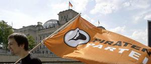Ein Mitglied der Piratenpartei läuft mit Fahne am Ufer vor dem Berliner Reichstagsgebäude