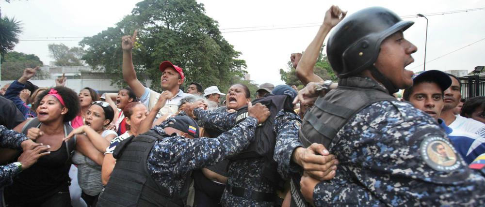 Polizeibeamte versuchen, Anhänger von Präsident Maduro während einer Kundgebung in Schach zu halten.