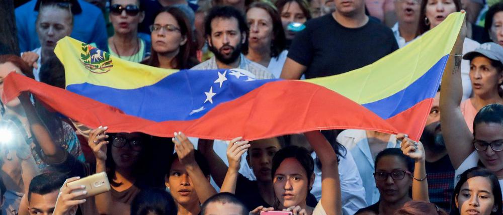 Menschen hören Venezuelas selbst ernanntem Interimspräsidenten Juan Guaido in Caracas während einer Kundgebung zu.
