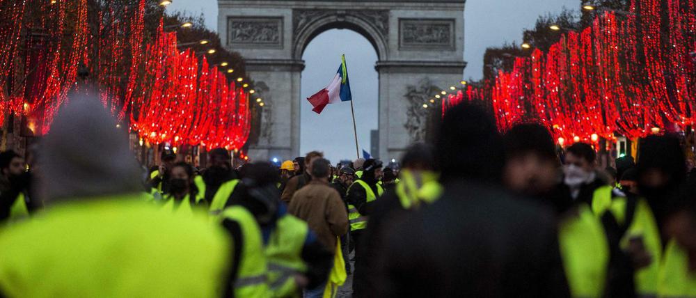 Frankreich, Paris: Demonstranten stehen vor dem Arc de Triomphe. Bei den Demonstrationen der «Gelben Westen» in Paris . Die Polizei setzte Tränengas und Wasserwerfer ein.
