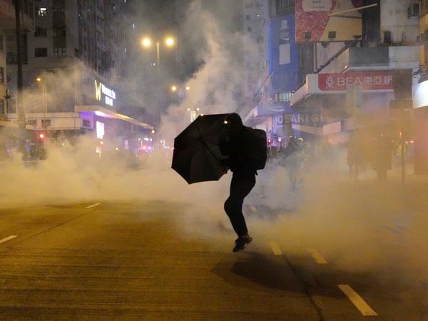 Ein regierungskritischer Demonstrant schützt sich mit einem Regenschirm vor Tränengas.