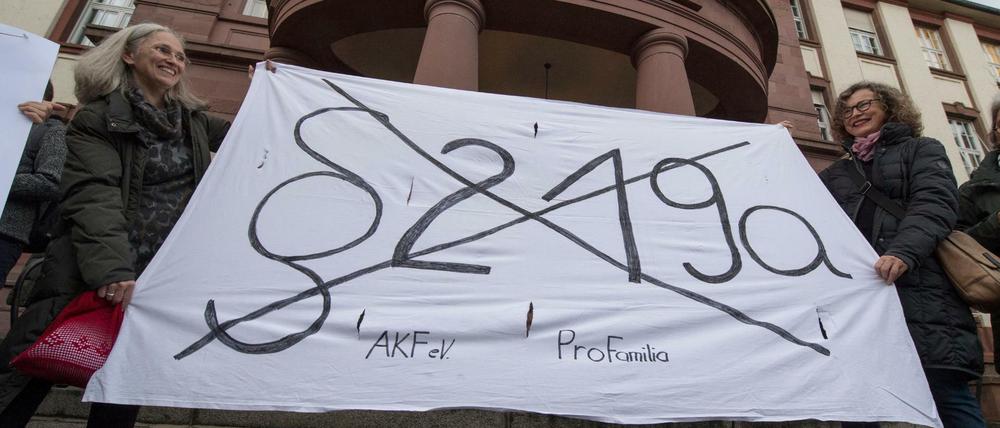 Mit einem Transparent fordern Demonstrantinnen am Freitag vor dem Amtsgericht in Gießen (Hessen) die Abschaffung des Paragrafen 219a.