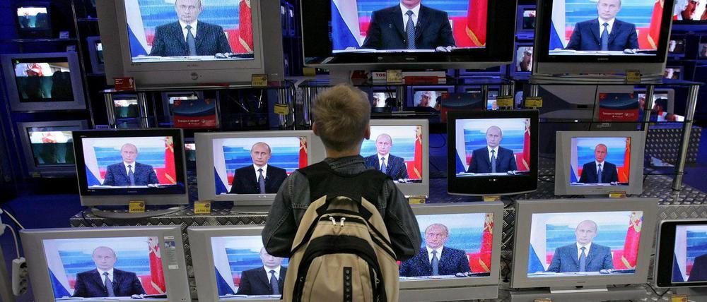 Ein Kind schaut sich Putin im Fernsehen an.