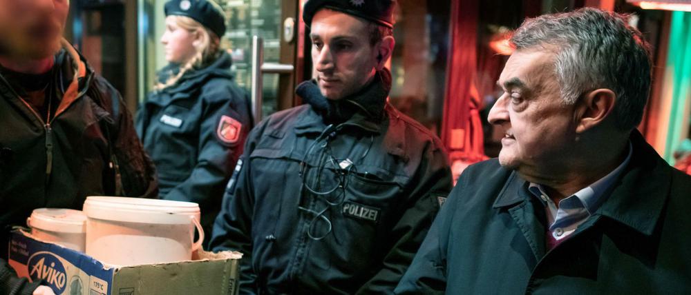 Herbert Reul (CDU, r), Innenminister von Nordrhein-Westfalen, verfolgt, wie nach einer Razzia Beweismittel aus einer Shisha-Bar getragen werden.
