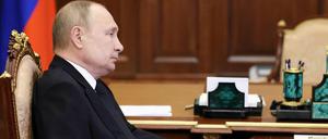 Der russische Präsident Wladimir Putin sitzt während einer Telefonkonferenz an seinem Schreibtisch in Moskau. 