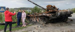 Ein Paar posiert für einen Foto vor einem zerstörten russischen Panzer bei Kiew.