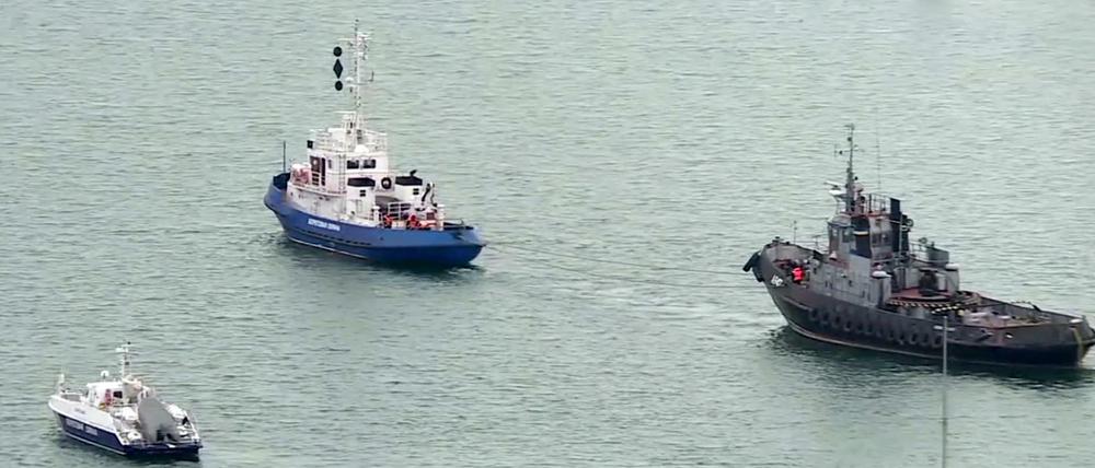 Ein beschlagnahmtes ukrainisches Schiff (r) wird von einem russischen Küstenwachboot aus dem Hafen von Kertsch geschleppt. 