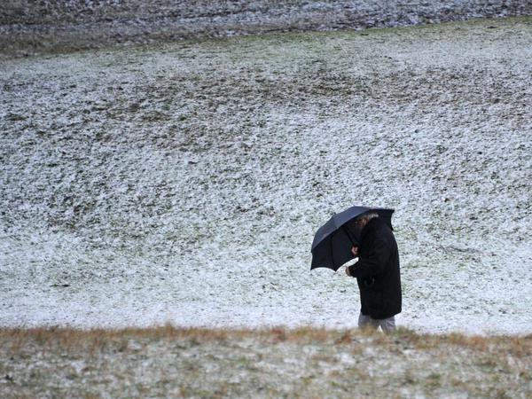 Ein Mann schützt sich vor einem Schneetreiben.
