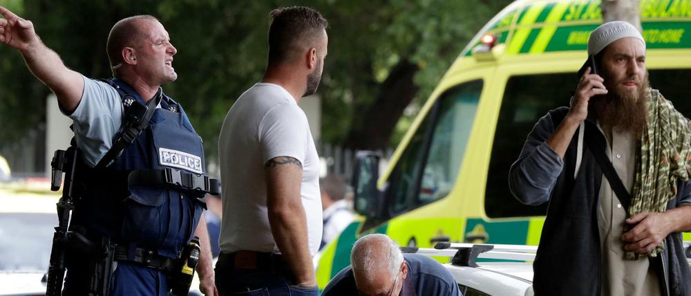 Ein Polizist versucht den Bereich nahe eines der Tatorte des Terroranschlags in Christchurch zu räumen.