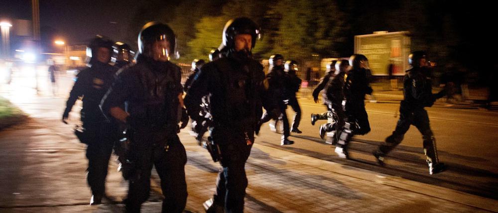 Polizisten verfolgen linke Demonstranten nach einem gewalttätigen Zusammenstoß am 23.08.2015 in Heidenau (Sachsen). Bei Protesten von Anwohnern und Rechtsextremen gegen eine neue Flüchtlingsunterkunft war es hier zuvor zu Ausschreitungen gekommen.