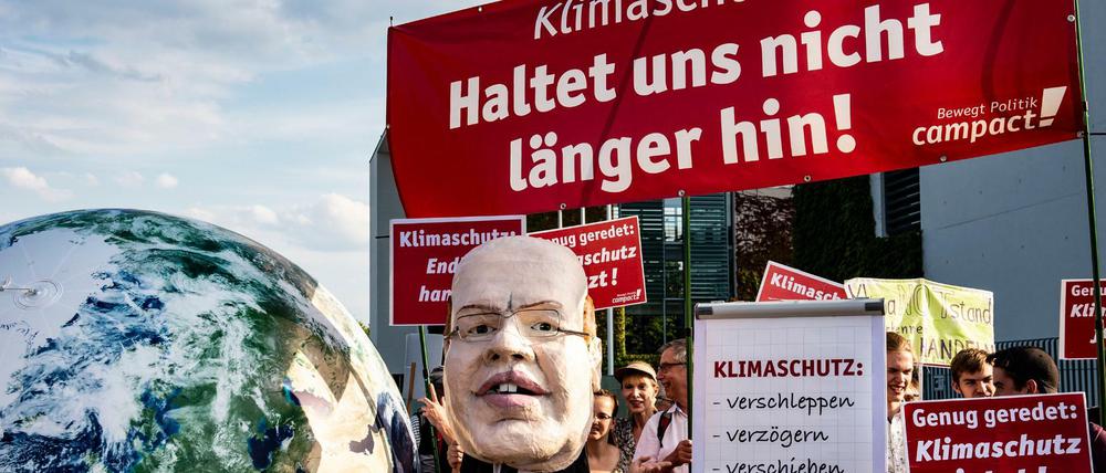 Demonstranten mit Transparenten und einer Maske von Wirtschaftsminister Altmeier stehen vor Beginn Sitzung des Klimakabinetts vor dem Bundeskanzleramt.