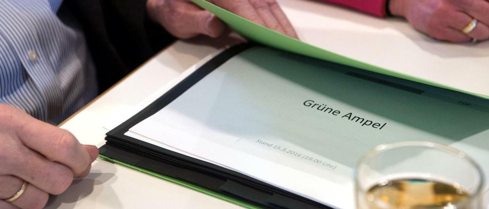 Der baden-württembergische Ministerpräsident Winfried Kretschmann hat im Haus der Architekten in Stuttgart (Baden-Württemberg) eine Mappe in der Hand, in der ein Dokument mit der Aufschrift "Grüne Ampel" liegt. 