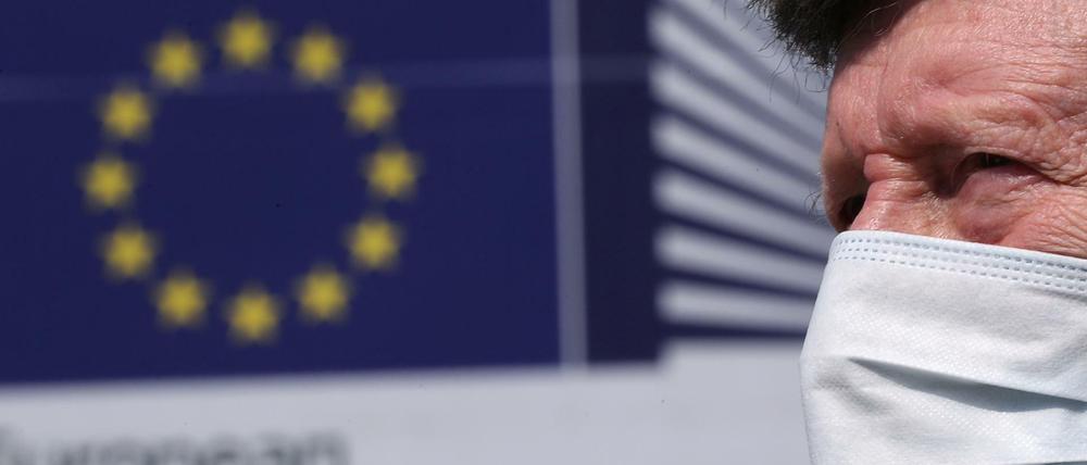 Mann mit einer Gesichtsmaske vor dem Sitz der EU-Kommission in Brüssel 