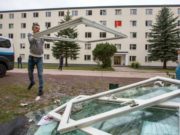 Ein Flüchtling wirft am 20.08.2015 vor der Erstaufnahmeeinrichtung in Suhl (Thüringen) ein zerstörtes Fenster auf einen Haufen. 