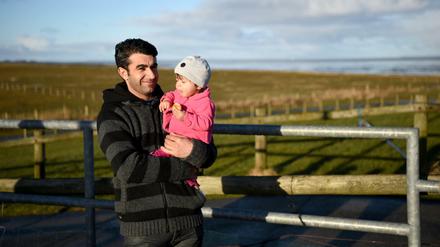 Der Syrer Ahmed Alsamiye steht auf der Hallig Langeneß (Schleswig-Holstein) mit seiner einjährigen Tochter Halasham auf der Warft. Die Flüchtlingsfamilie aus Syrien hat auf der Hallig Langeneß ihr neues Zuhause gefunden.