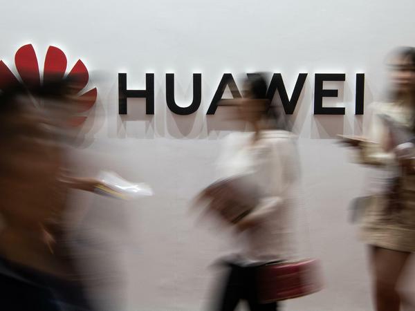 Besucher einer Technik-Messe in Peking vor einem Huawei-Logo. 
