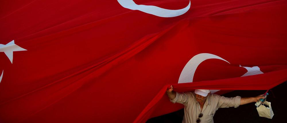 Ein Mann steht unter einer riesigen Türkei-Flagge in Istanbul.