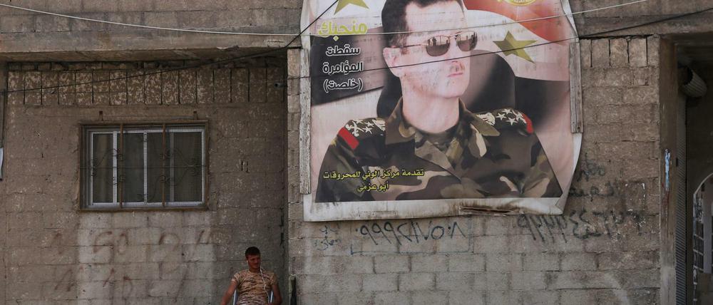 Ein syrischer Soldat sitzt in Ost-Ghouta neben einem Poster des syrischen Präsidenten Baschar al Assad. 