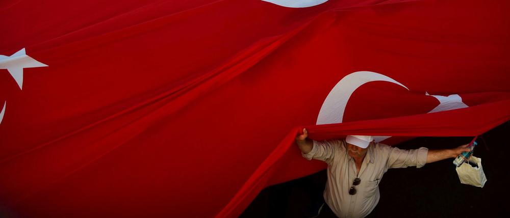 Ein Mann unter einer riesigen türkische Flagge in Istanbul 