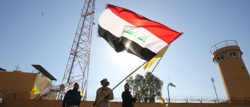 Demonstranten schwenken die Flagge des Irak vor der US-Botschaft in Baghdad.
