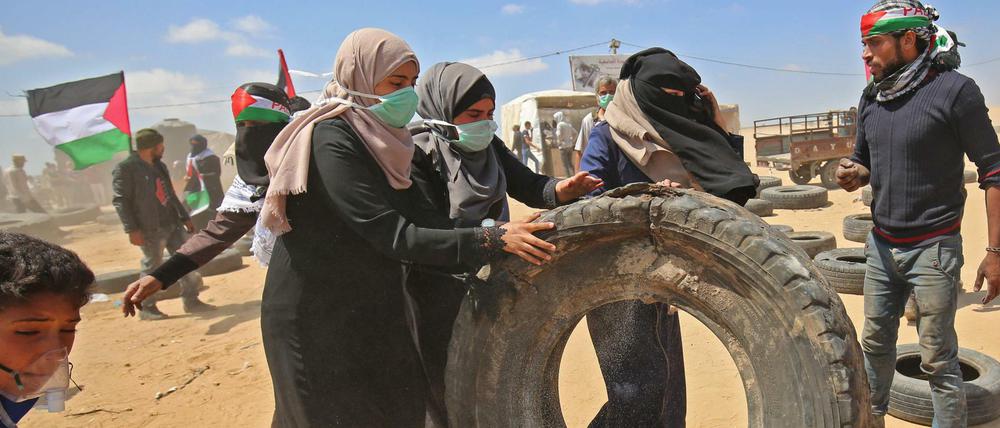 Palästinenserinnen sammeln Lkw-Reifen, die in Brand gesteckt werden sollen. Der Rauch soll den israelischen Soldaten die Sicht nehmen.
