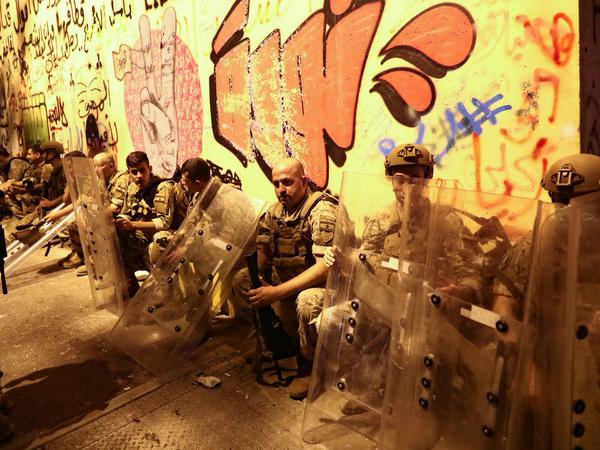 Soldaten hocken in der Nacht zu Freitag mit ihrer Ausrüstung vor einer Mauer.