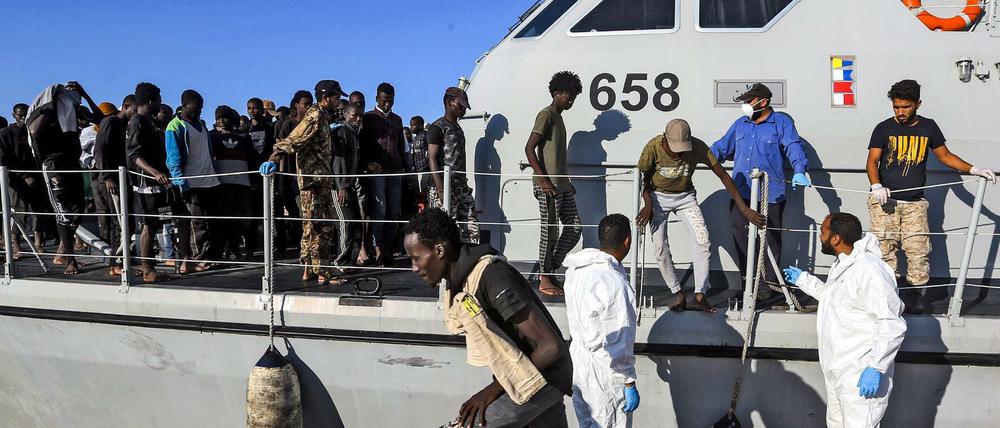 Gerettete Migranten verlassen ein Schiff der libyschen Küstenwache.