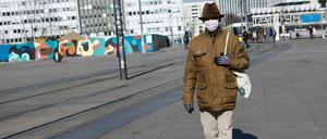 Ein Mann in Schutzmaske läuft auf dem Alexanderplatz.