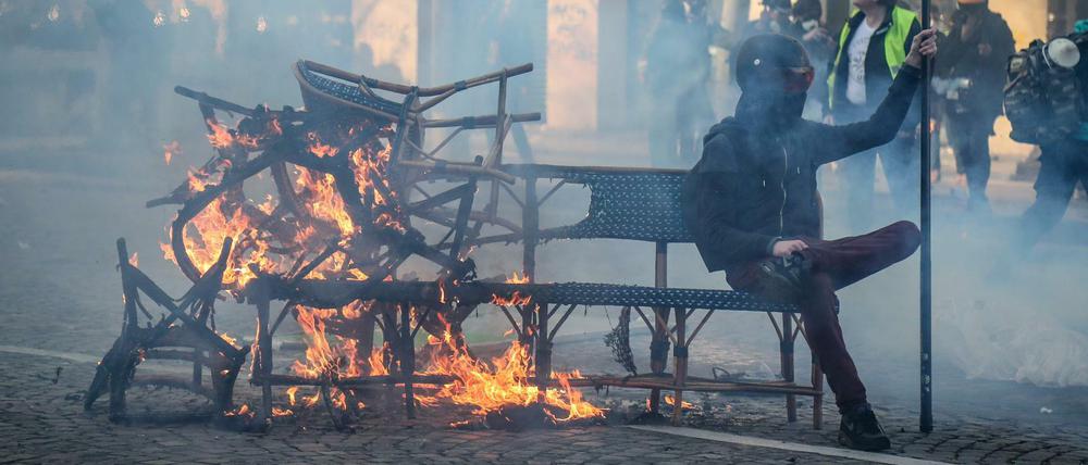 Ein Demonstrant sitzt bei den "Gelbwesten"-Protesten am 16. März in Paris auf einer brennenden Bank. 