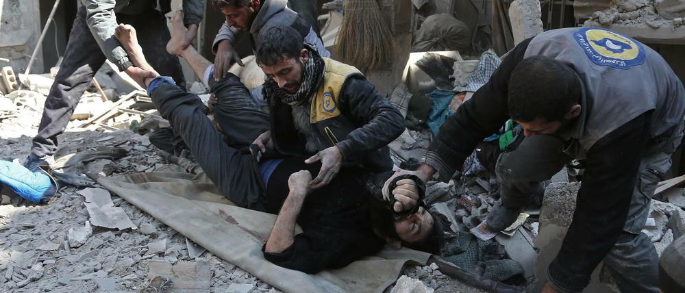 Ein verletzter Mann wird von syrischen Helfern aus einem zerstörten Haus in Hamouria geborgen.