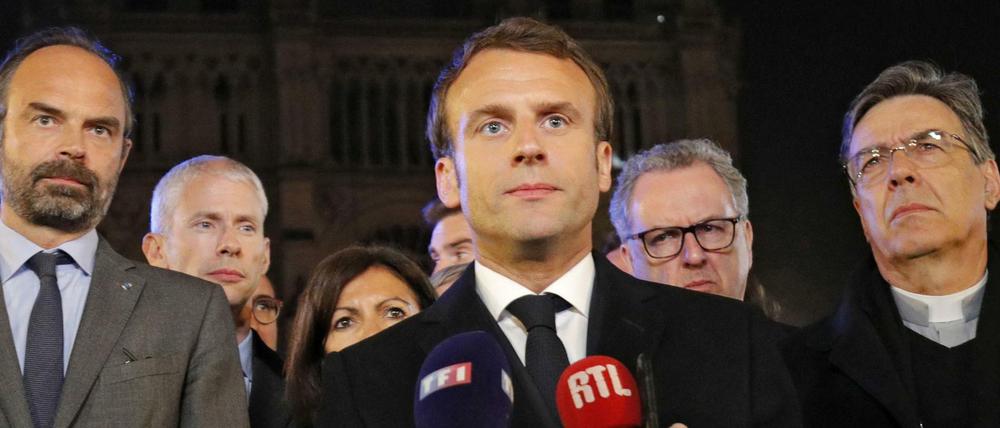 French President Emmanuel Macron (C) is accompanied by Mayor of Paris Anne Hidalgo (3L), French Prime Minister Edouard Philippe (L) French Culture Minister Franck Riester (2L) and Archbishop of Paris Michel Aupetit (R) as he speaks at Notre-Dame Cathedral in Paris on April 15, 2019, after a fire engulfed the building. - A fire broke out at the landmark Notre-Dame Cathedral in central Paris, potentially involving renovation works being carried out at the site, the fire service said.Images posted on social media showed flames and huge clouds of smoke billowing above the roof of the gothic cathedral, the most visited historic monument in Europe. (Photo by PHILIPPE WOJAZER / POOL / AFP)