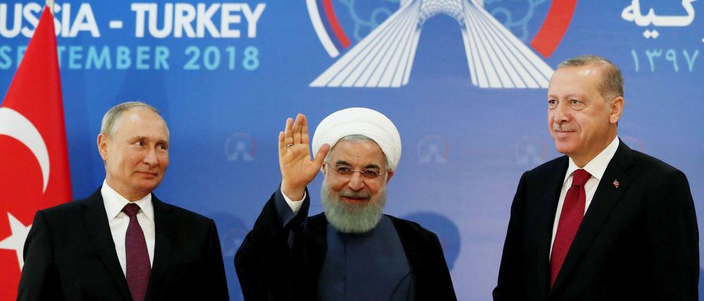 Der türkische Präsident Recep Tayyip Erdogan (r.) , der iranische Präsident Hassan Rouhani (M.) und der russische Präsident Wladimir Putin winken ins Publikum. 