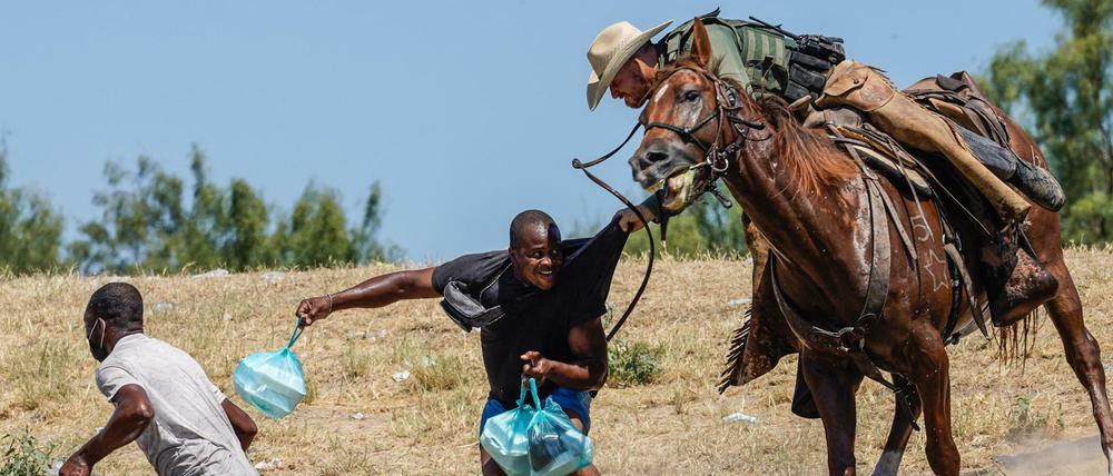 Ein US-Grenzschützer greift nach einen Migranten aus Haiti. 